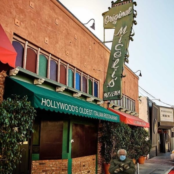 Miceli's Italian Restaurant exterior with green awning, stained glass windows, and a person in a mask.